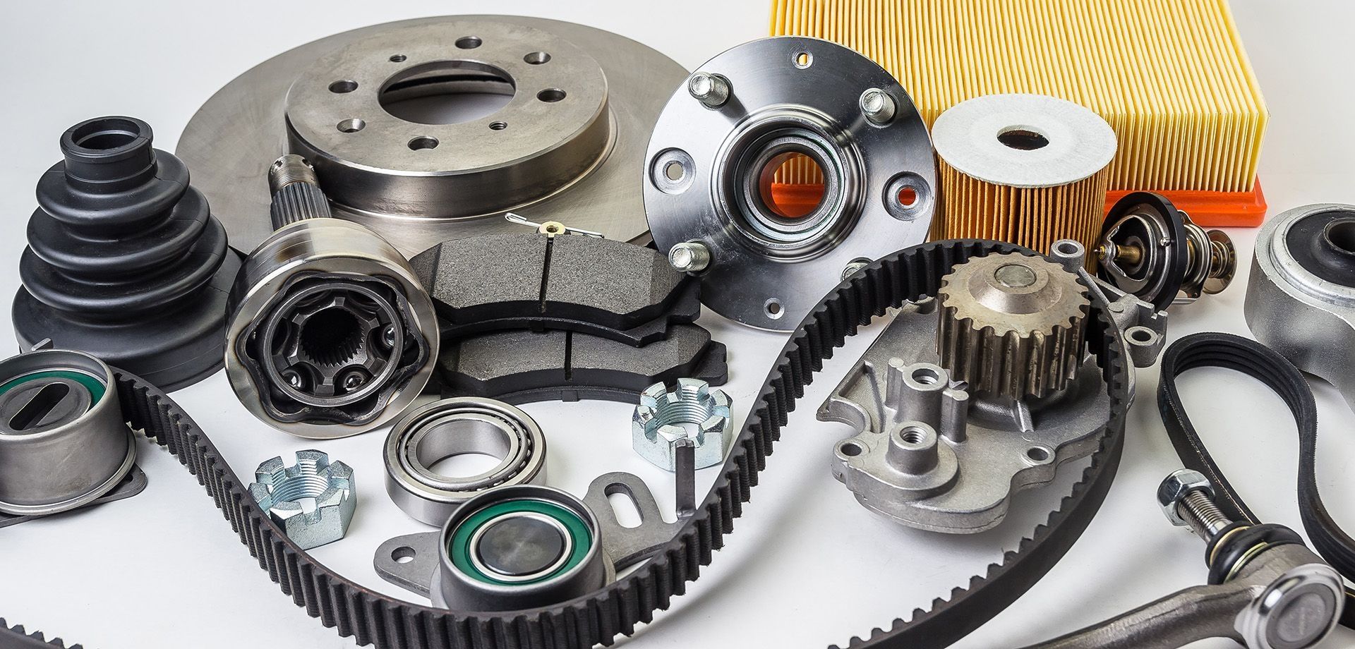 Einige Ersatzteile für jegliche Autos die auf einer weißen Oberfläche liegen.